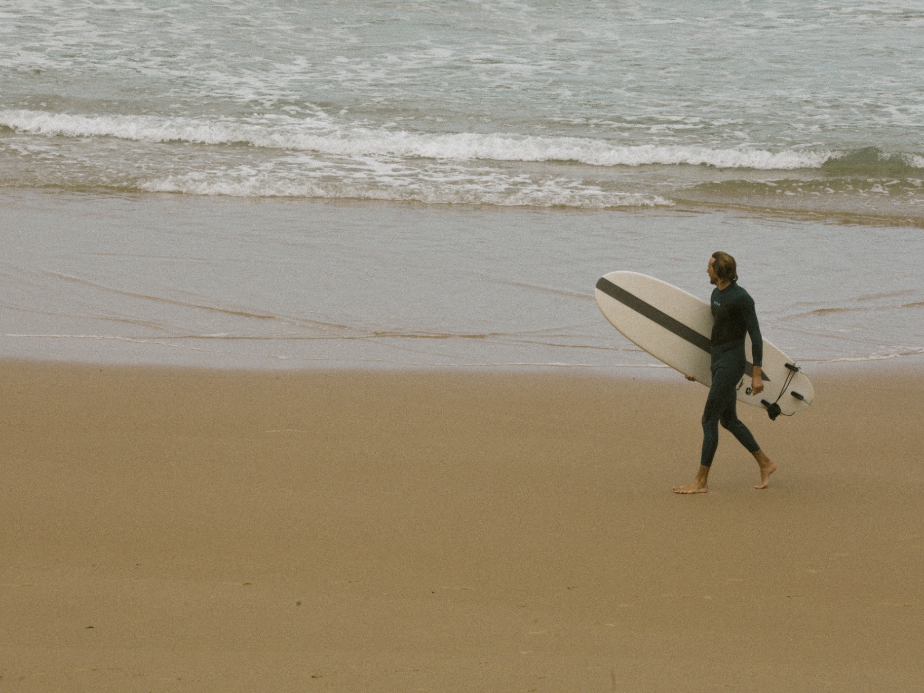 Surfeur marchant seul sur la plage à Biarritz