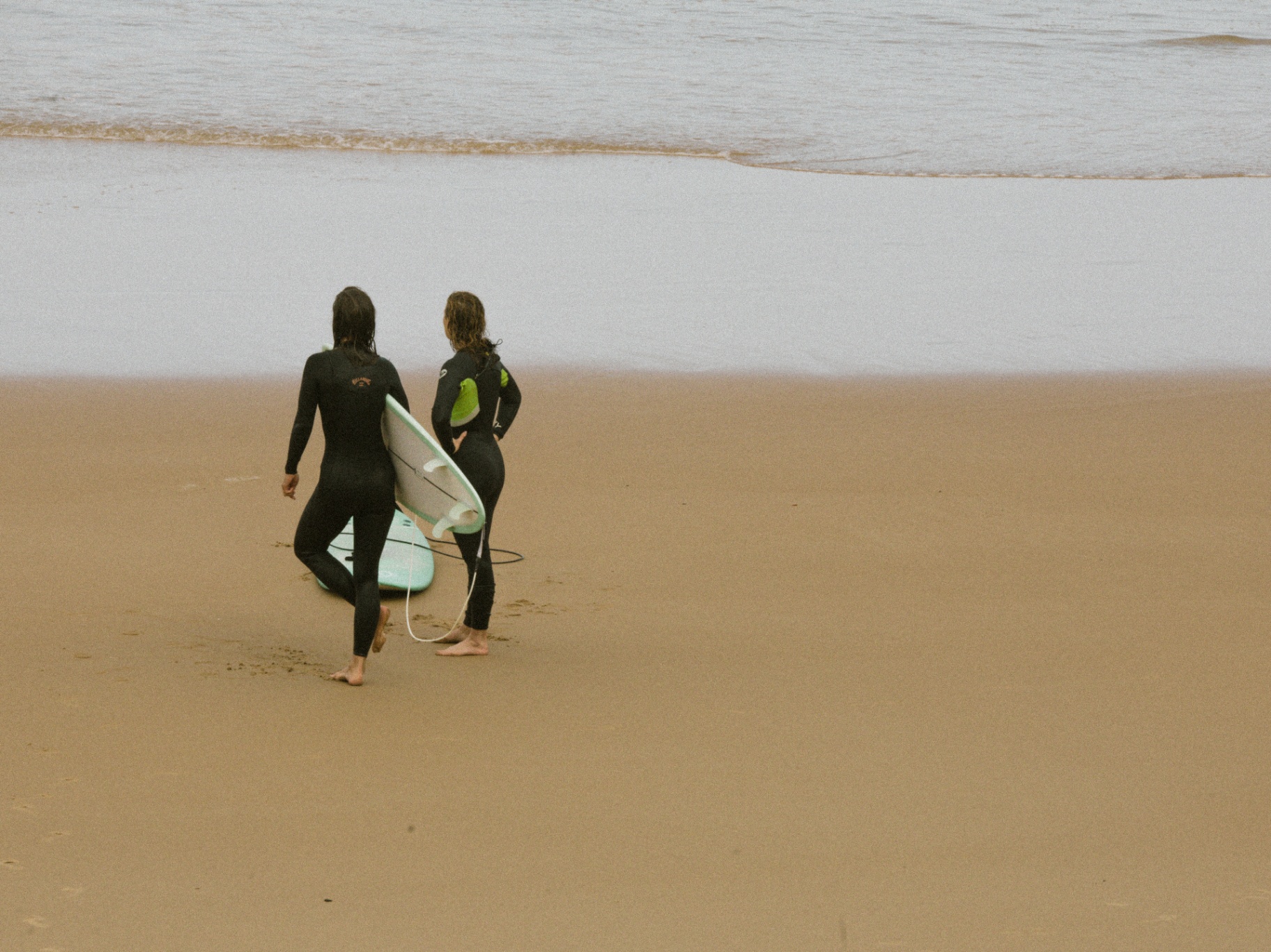 Deux surfeurs marchent vers l'océan, planche sous le bras